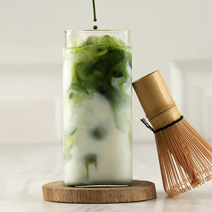 Iced matcha milk drink with a bamboo whisk